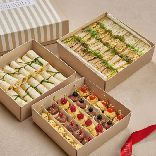 Three cardboard boxes containing various food items on a beige surface.