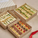 Three cardboard boxes containing various food items on a beige surface.